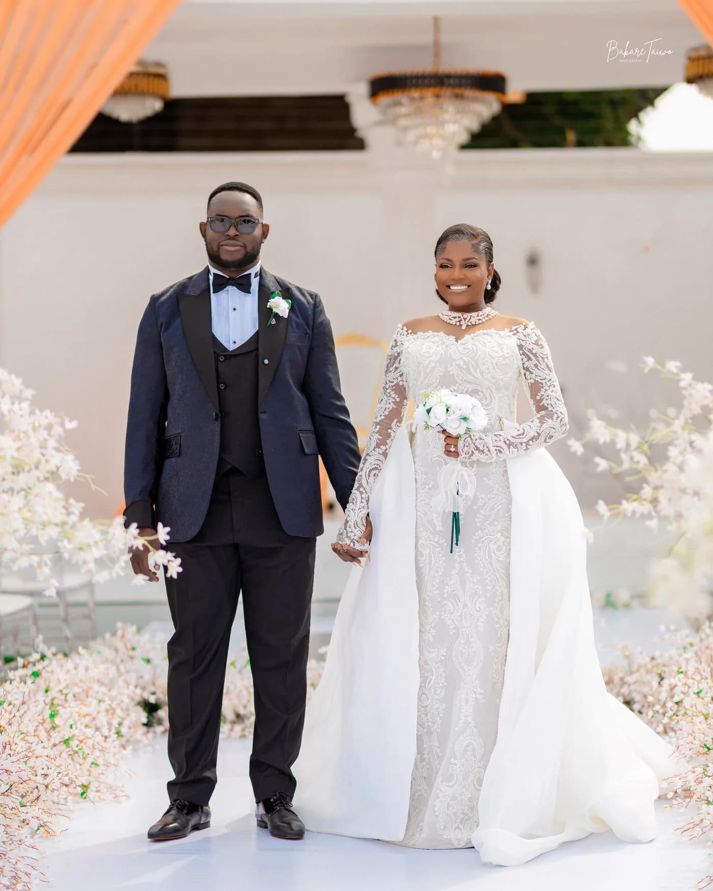 A couple stands together beneath a ceremony arch.